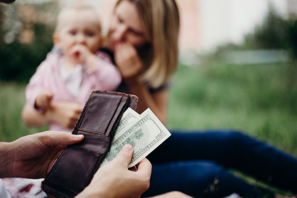 man getting money out of wallet with child and woman in the background